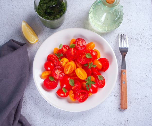 Salade van verse kerstomaatjes, mozzarella, basilicum en andere groenten op tafel