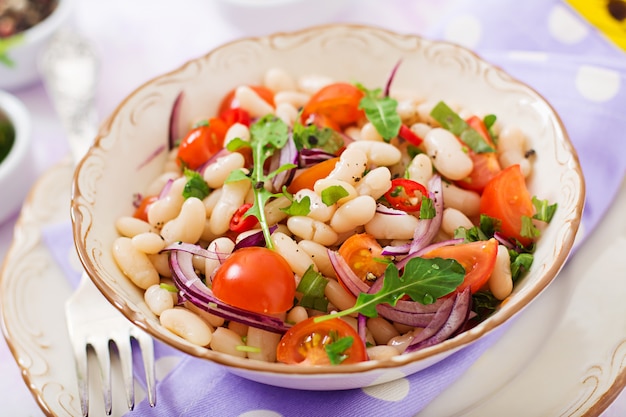 Salade van witte bonen, tomaat, rucola, rode ui en peper in kom.