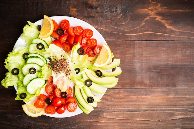 Saladebar op plaat met tomaten, komkommer, sla, avocado en zaden met citroensap