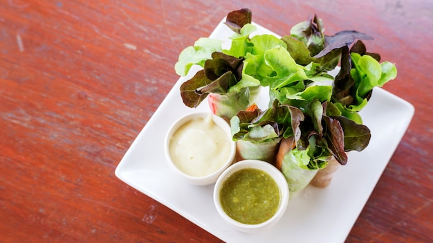 Saladebroodje en slasaus op een witte plaat.