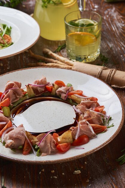 Salades met gekookt varkensvlees op een houten tafel met sauzen