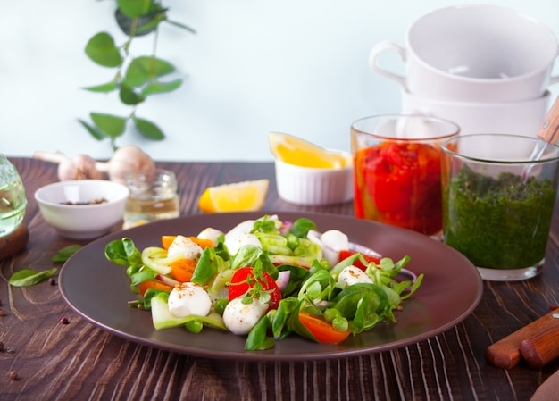 Salads of fresh cherry tomatoes, mozzarella, basil, radish and other greens on the dinner table