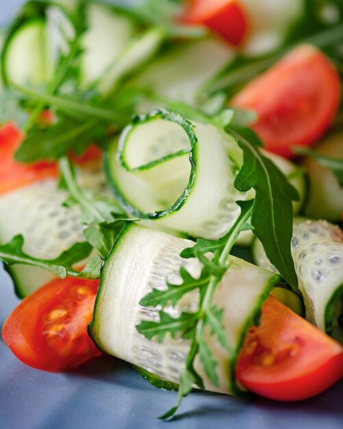 Salads of tomatoes cucumbers and arugula on a blue plate suddenly open