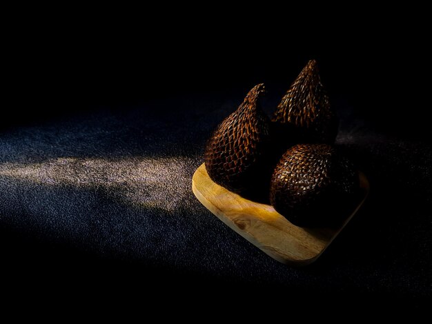 Salak is a type of palm fruit commonly eaten snake fruit its\
scientific name is salacca zalacca black sand background