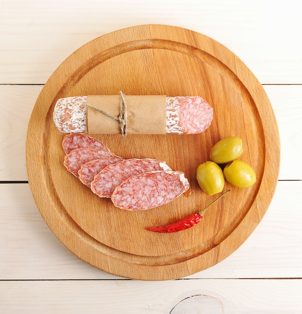 Salami, chilli and olives on wooden surface