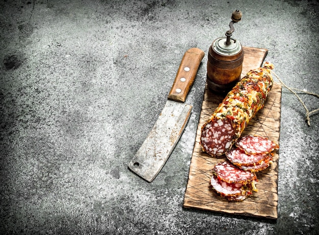 Salami on a cutting board with an old hatchet on a rustic background