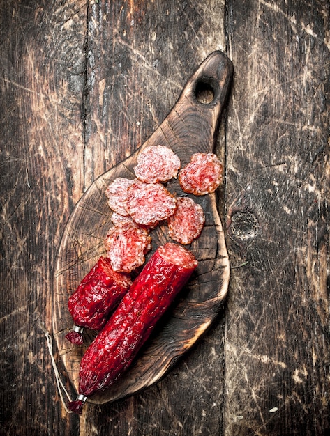 Salami met kruiden en specerijen op een bord op een houten achtergrond