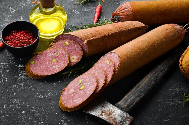 Salami met pistachenoten, hazelnoten en rozemarijn en kruiden op een zwarte achtergrond Bovenaanzicht Rustieke stijl