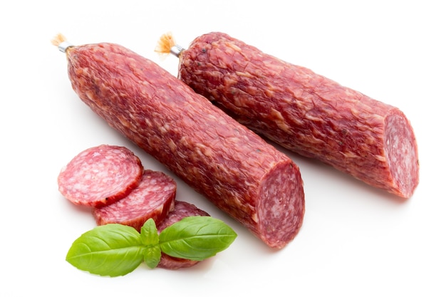 Salami rookworst, basilicumbladeren en peperkorrels geïsoleerd op een witte ondergrond.