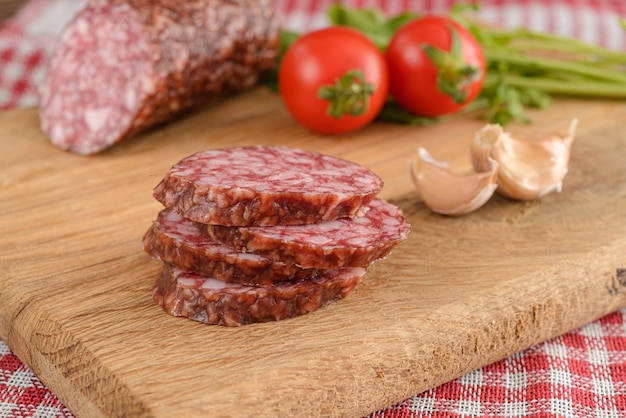 Salami sausage cut slices with tomato and garlic on wooden table