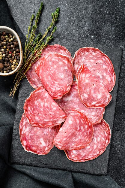 Salami sausage slices on a black chopping board