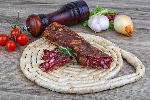 Salami sausage with rosemary on the wood background