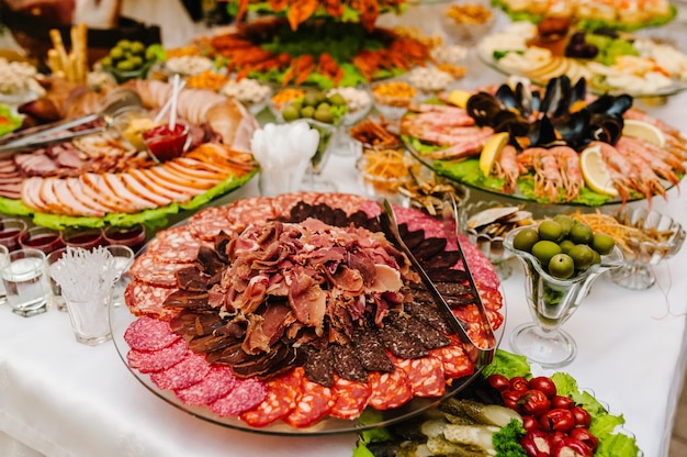 Salami, sliced ham, sausage, cured pork meat, Italian prosciutto, bacon. Meat antipasto platter on  table.