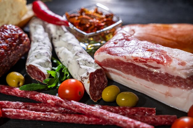 Salami, sliced ham, sausage, prosciutto, bacon. Meat antipasto platter on wooden table.