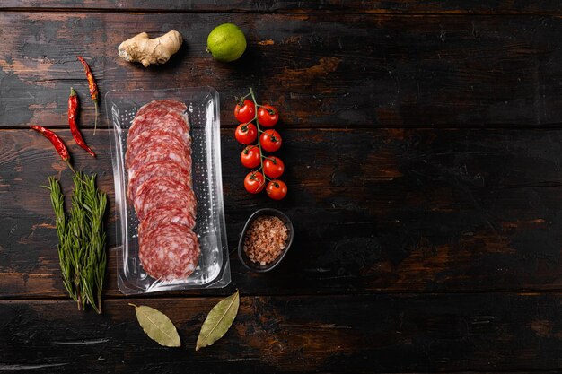 Salami slices vacuum plastic pack set, on old dark  wooden table background, top view flat lay, with copy space for text