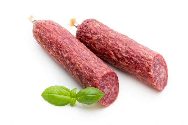 Salami smoked sausage, basil leaves and peppercorns isolated on white.