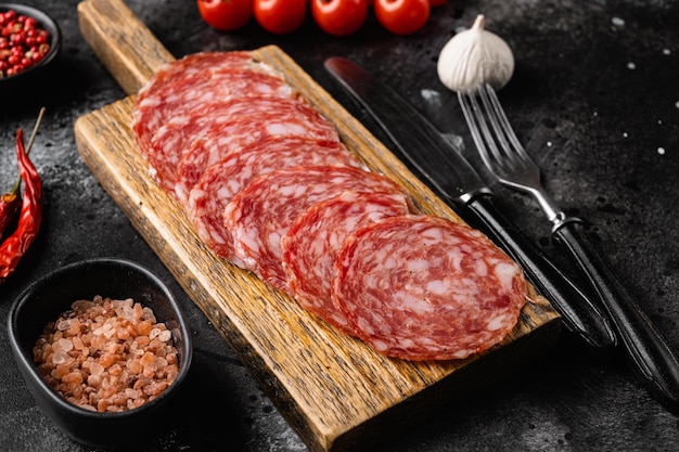 Salami smoked sausage set, on black dark stone table background