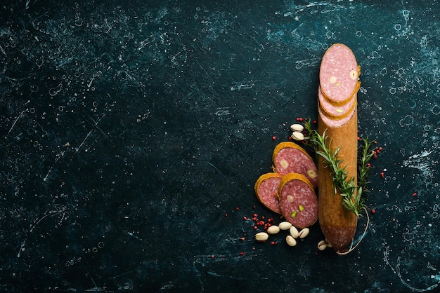 Salami with pistachios hazelnuts and rosemary and spices on a black background Top view Rustic style