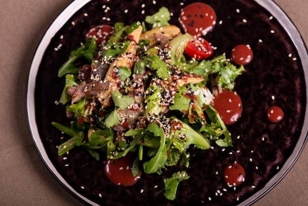 Salat van rucola en vlees op een zwarte plaat