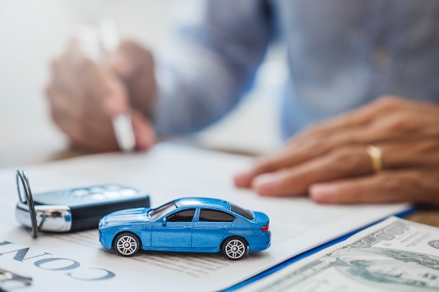 Foto l'agente di vendita stipula un contratto di prestito auto di successo con il cliente e firma un contratto