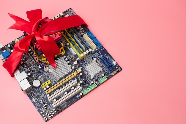 Photo sale of computer components, motherboard in red ribbon, on pink background, banner, copy space