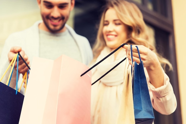 Фото Продажа, потребление и концепция людей - крупный план счастливой пары, смотрящей в сумку для покупок в витрине магазина на городской улице