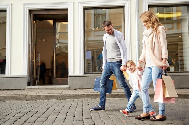 Foto vendita, consumismo e concetto di persone - famiglia felice con bambino e borse della spesa in città