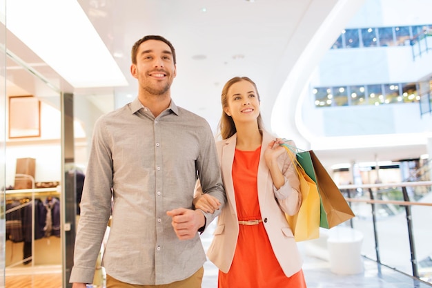 Sale, consumerism and people concept - happy young couple with shopping bags walking in mall