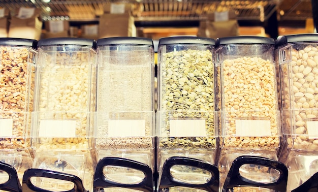 sale and eco food concept - row of jars with nuts and seeds at grocery store