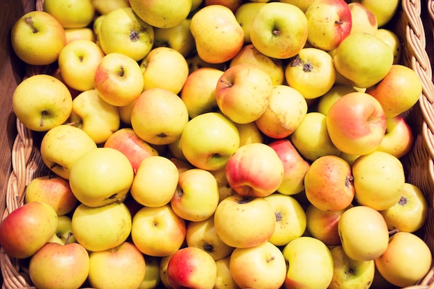 sale, farming, harvest, agriculture and eco food concept - ripe apples in basket at bio market or farm