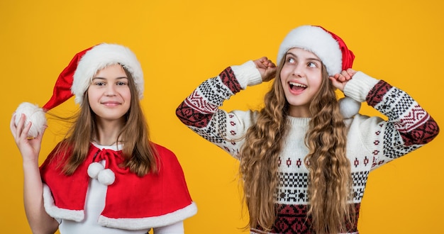 Vendita per regali e regali. concetto di amicizia. bambini felici di babbo natale. bambini sorridenti in cappello e maglione rossi della santa. festeggiare le vacanze invernali. tempo di shopping natalizio. le ragazze adolescenti sentono la felicità.