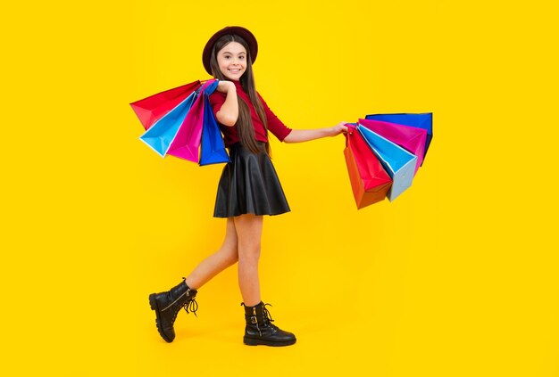 Sale and shopping concept Teen girl holding shopping bags isolated on studio background Happy teenager portrait Autumn shopping sale Smiling girl