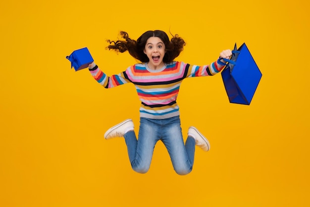 Sale and shopping concept teen girl holding shopping bags isolated on studio background happy teenager positive and smiling emotions of teen girl run and jump