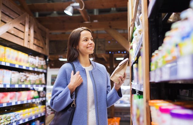 販売、ショッピング、消費主義、人々の概念-市場で食べ物を選んで買う幸せな若い女性