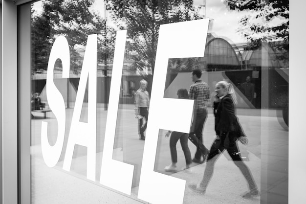 Photo sale text on store window with reflection of people