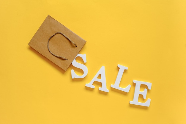 Sale text with paper bag against yellow background