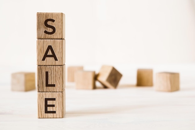 SALE word made of wooden cubes on a light background whith blurred cubes