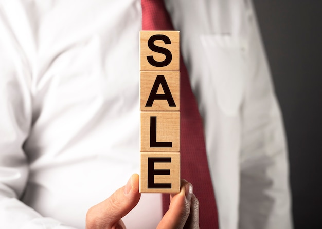 Sale word on wooden cube blocks in businessman hands