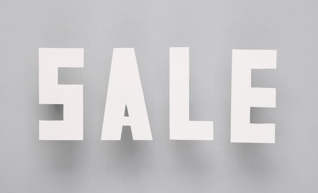 Sale words cut out of paper on a gray background