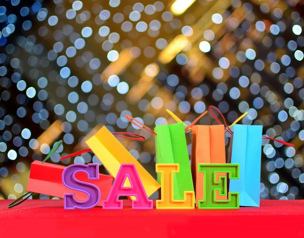 Photo sale written by colorful letters on the background of shopping bags on a bokeh background