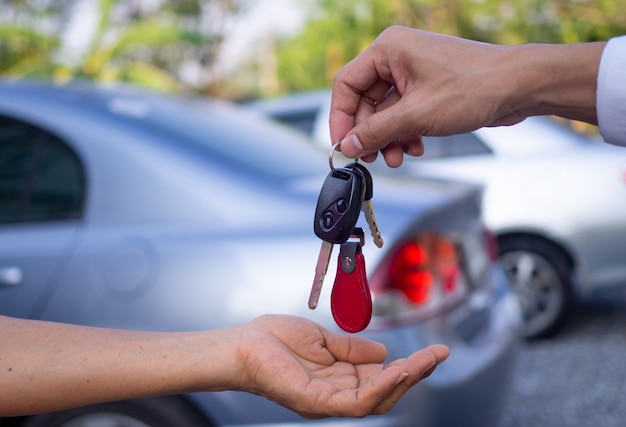 販売代理店は車を販売し、新しい所有者に鍵を渡しています。車やレンタカーを売る