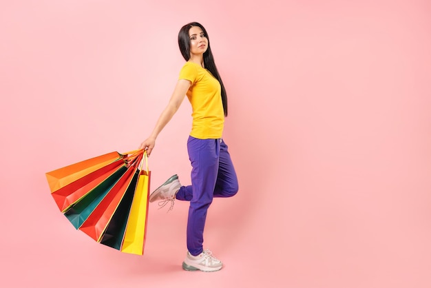 Концепция продаж. Девушка с цветными бумажными пакетами на розовом фоне