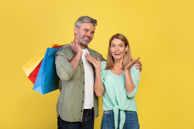 Sales and discounts Overjoyed woman and man holding many bright shopper bags after buying gifts and clothes