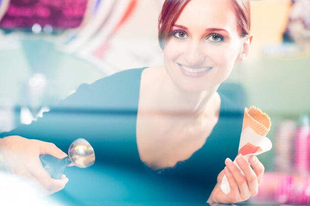 Foto la porzione della ragazza delle vendite s scoop di gelato per wafer