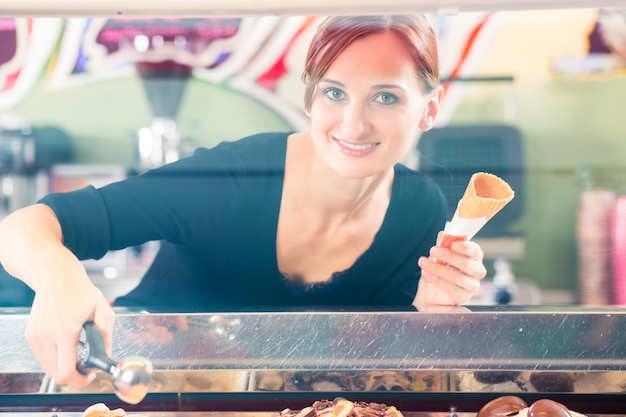 Sales girl portion s scoop  of ice cream to wafer