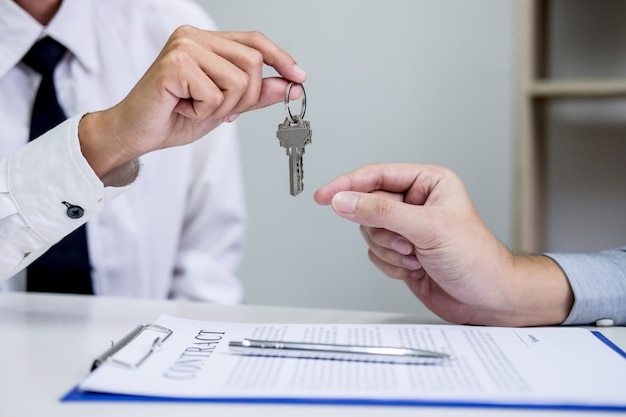 Sales manager giving keys to customer after signing rental lease contract of sale purchase agreement