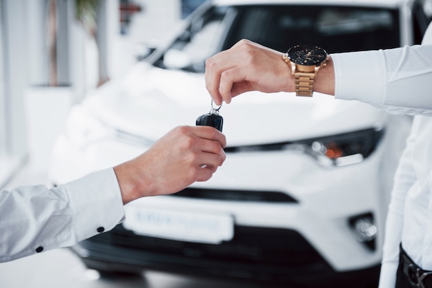 sales manager in suit selling the car to the customer.