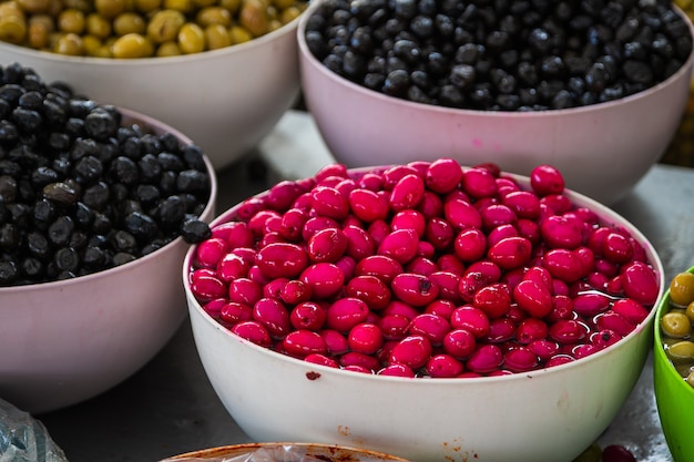 Sales of traditional products  Mediterranan olives  in the market Many bowls of black pink and green olives at the farmers market