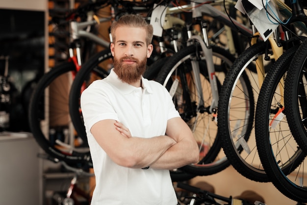 A salesman in a bicycle shop poses near a bicycle.