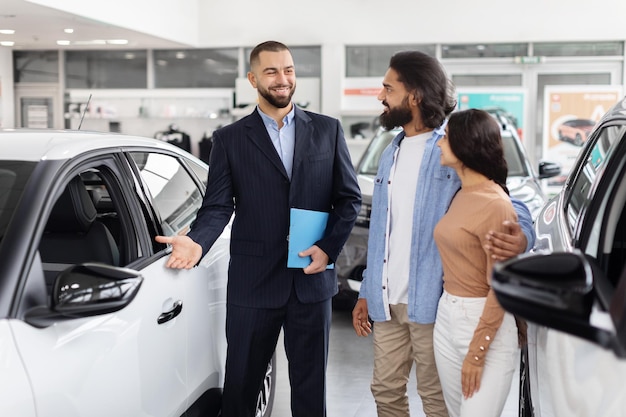 Salesman explaining car features to indian couple